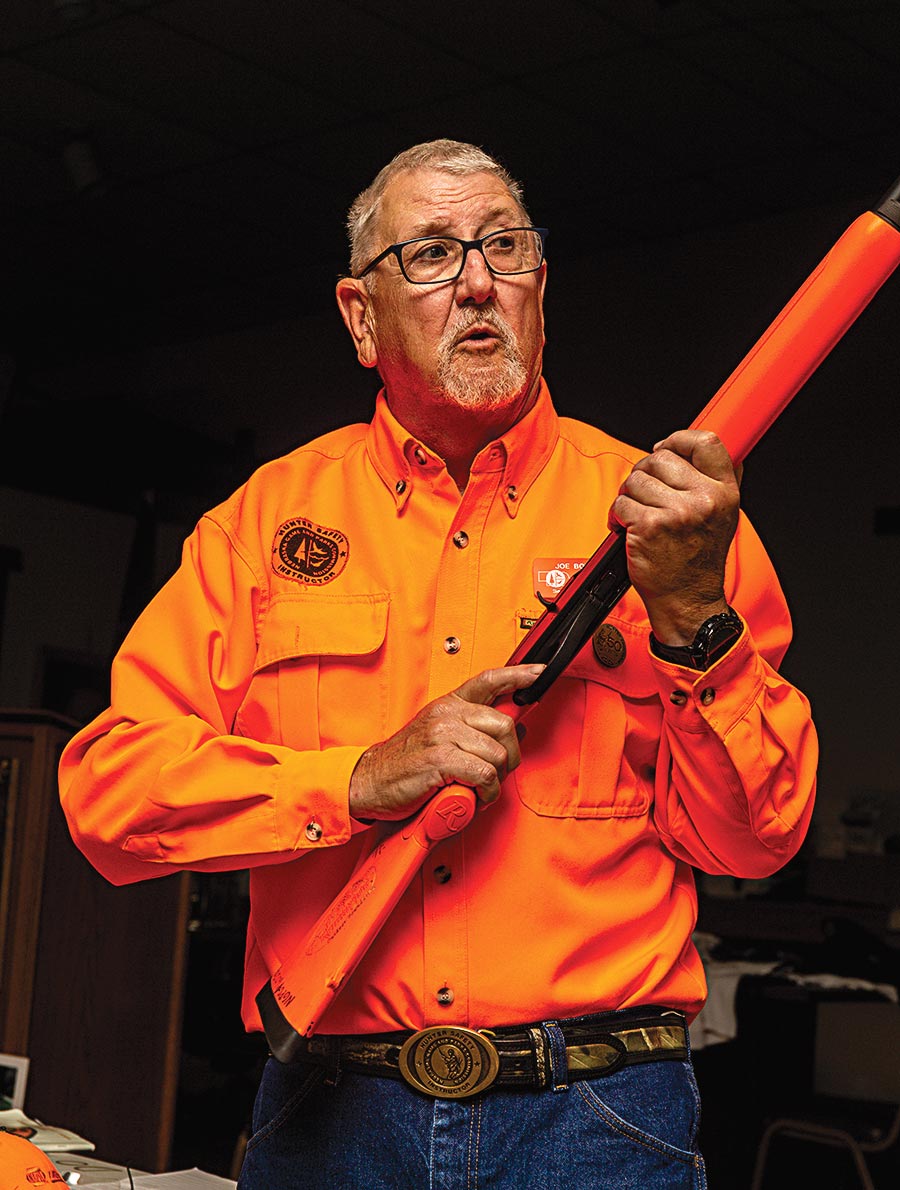 A hunter ed instructor teaching how to handle a firearm.