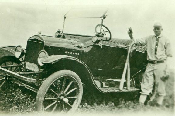 A man stands next to his car that is parks on the hill of a ditch