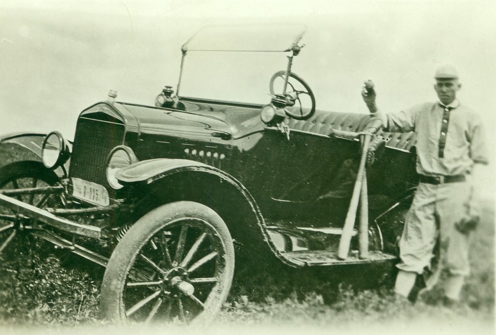 A man stands next to his car that is parks on the hill of a ditch 