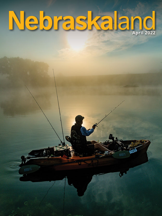 April 2022 Nebraskaland cover with an angler kayak fishing on a foggy lake.