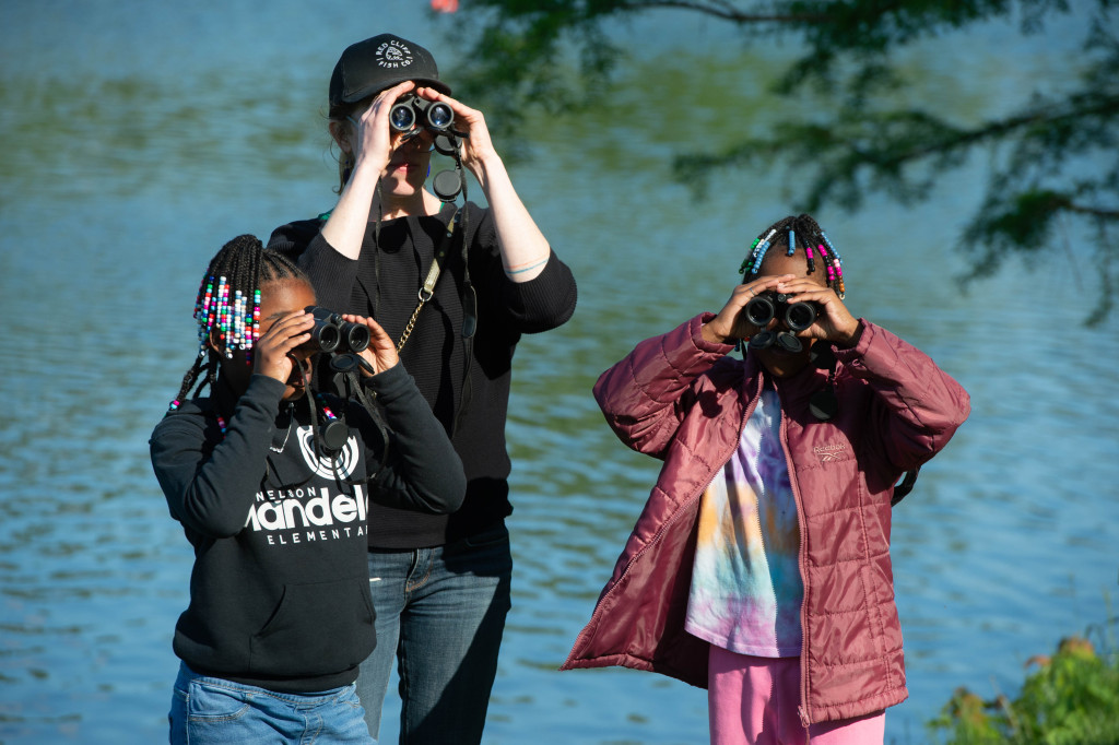 a woman and two girls hold binoculars to their faces