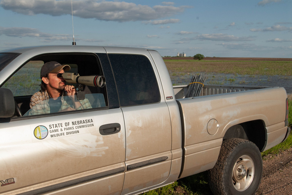 a man uses a long-telescope out of his truck window to look at birds