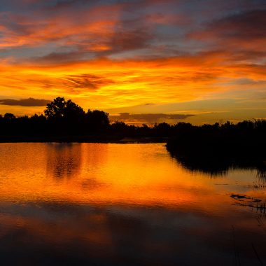 A vibrant summer sunset along a river.