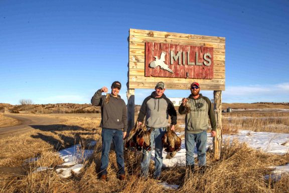 Three brothers with harvested pheasants on a Controlled Shooting Area.