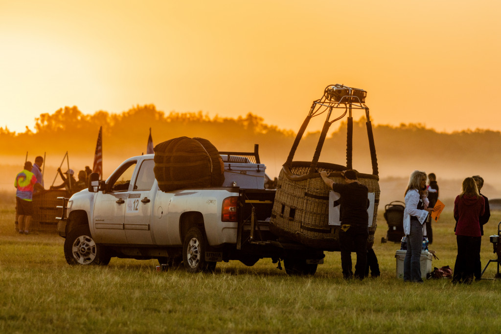 People unload a hot air balloon from a truck bed.