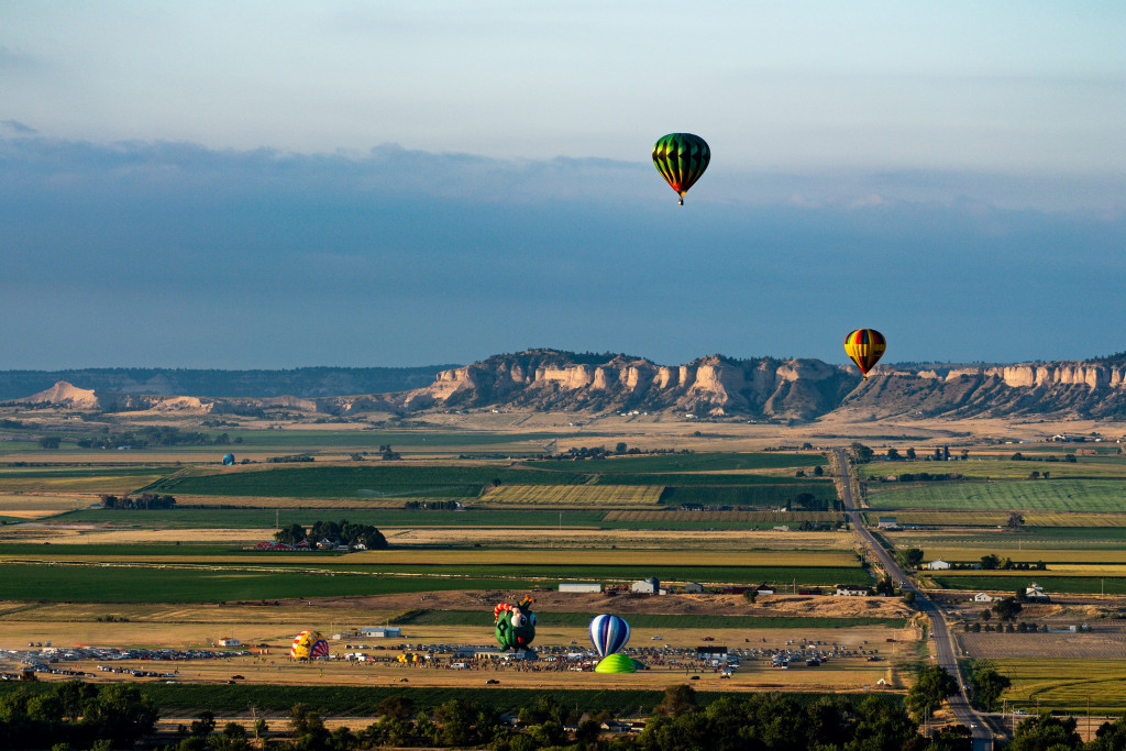 Hot air balloons float above Scotts Bluff County in northwestern Nebraska with Fort Robinson State Park in the background.