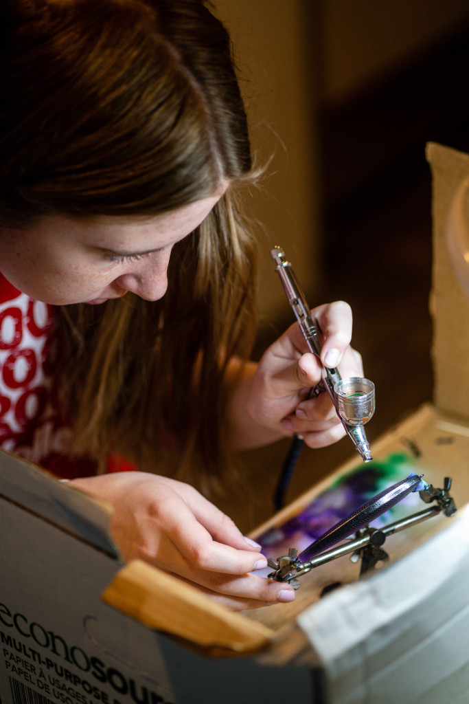 Kiera Haag uses an airbrush to paint a crankbait lure.