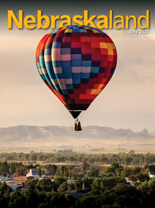 July 2021 cover of Nebraskaland featuring a hot air balloon floating above a small town.