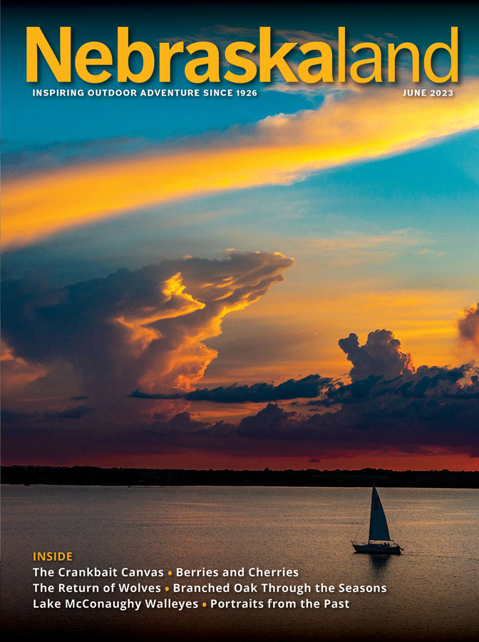 June 2023 Nebraskaland Magazine cover featuring a sailboat on lake at sunset.