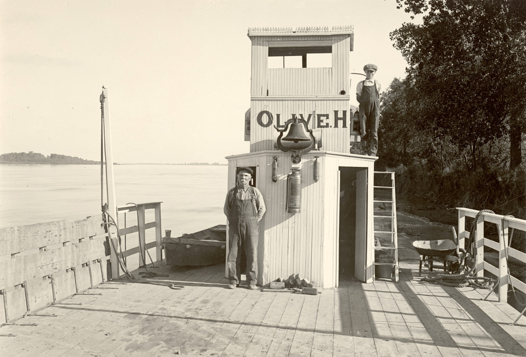 A man stands in overhauls in front of the captain's shed on a ferry