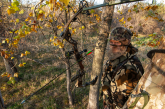 A bowhunter stands with hunting gear in a tree stand during deer season in Nebraska.