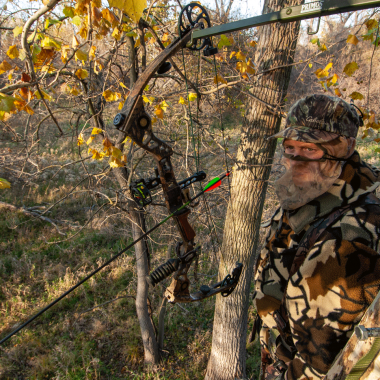 A bowhunter stands with hunting gear in a tree stand during deer season in Nebraska.