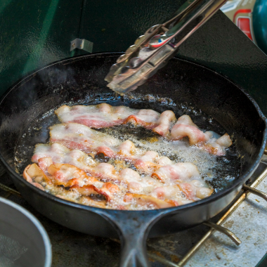 bacon fries in a cast-iron skillet