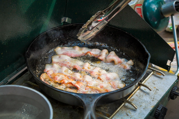 bacon fries in a cast-iron skillet