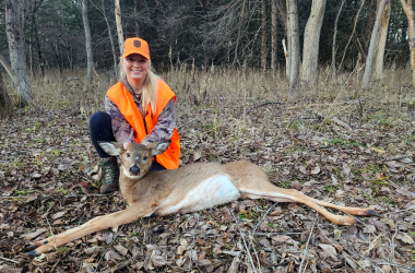 A woman poses with her harvested doe during deer hunting season.