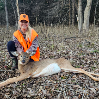 A woman poses with her harvested doe during deer hunting season.