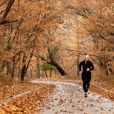 A woman running on a trail in the fall.