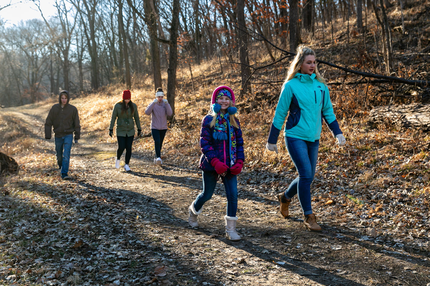 A mother and daughter hiking on a trail in the winter.