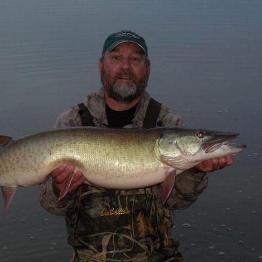 Angler holding muskellunge.