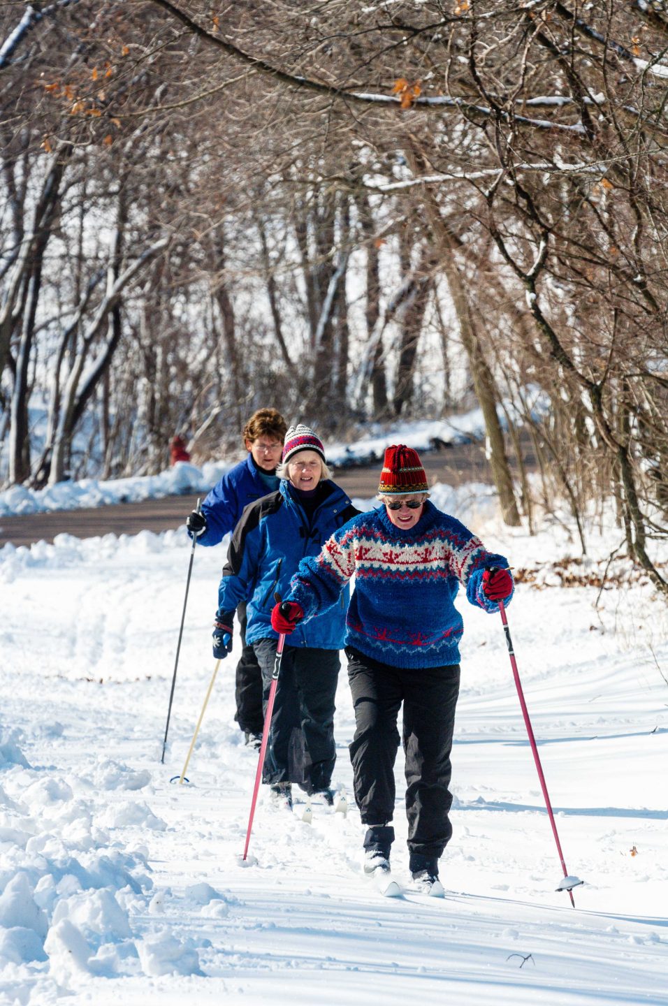 Three older women skiing in the snow.