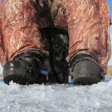 Boots with creepers next to an ice hole.