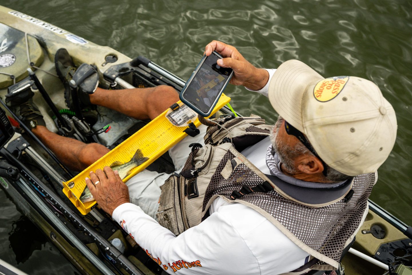 A measuring a bass while fishing from a kayak.