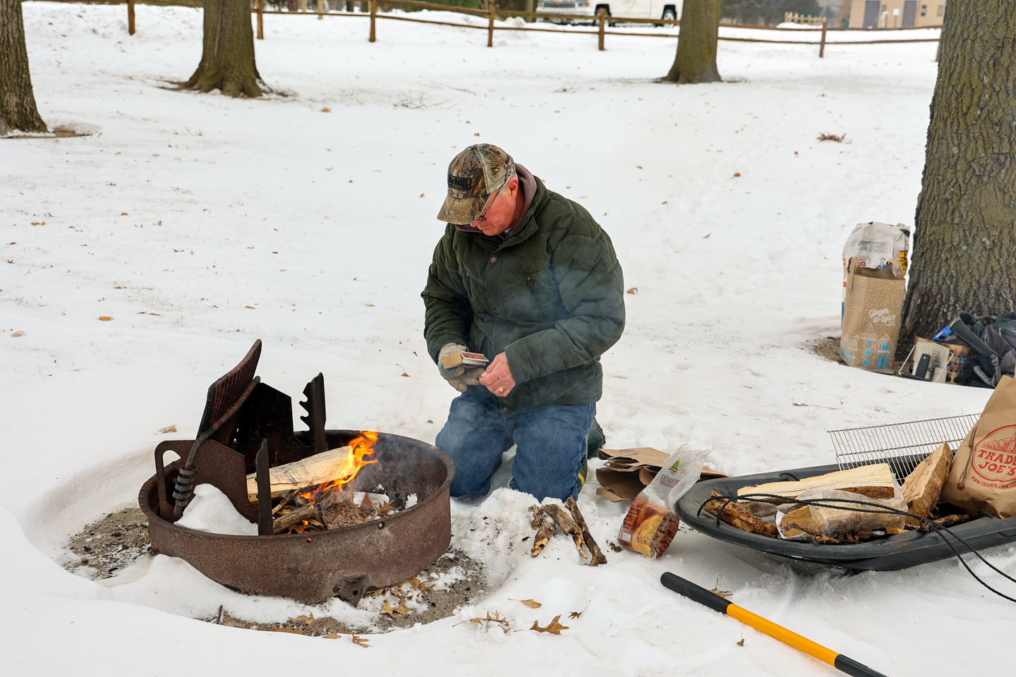 A man starting a campfire during winter on a snowy landscape.