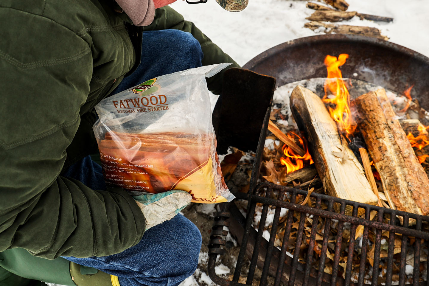 Adding more fatwood kindling to a campfire.