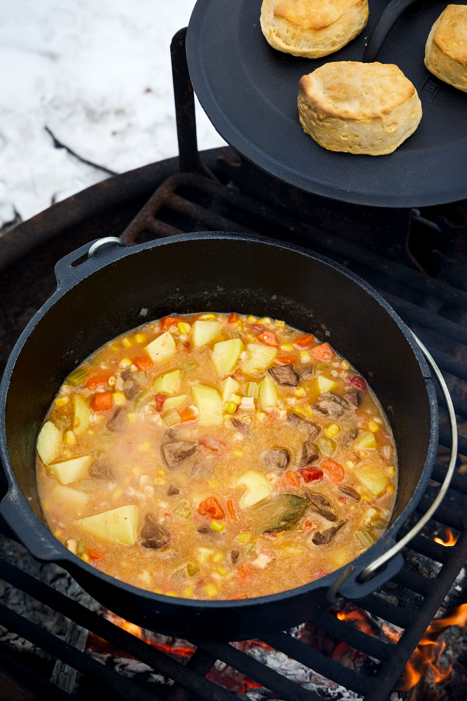 Venison stew heating up in a cast iron pot over a campfire.