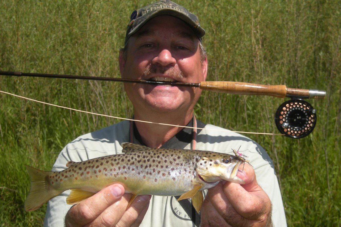 Fly angler holding brown trout.