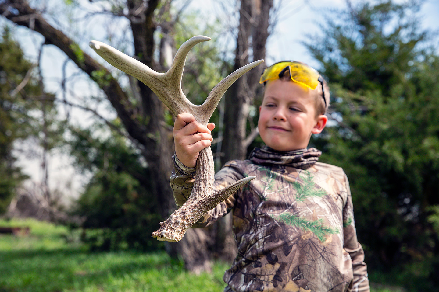 A boy holds up a deer shed he found outdoors.