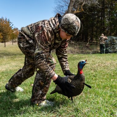 A boy setting up a turkey decoy for a hunt.