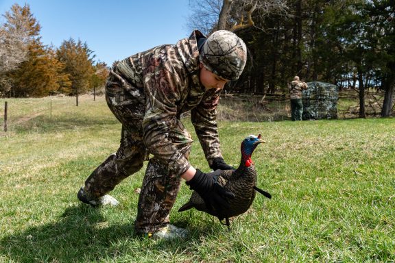 A boy setting up a turkey decoy for a hunt.