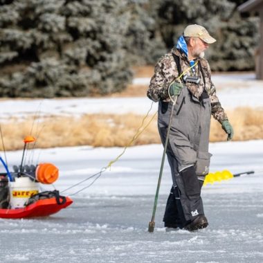 Angler pulling sled walking on ice.