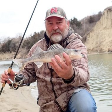 Shoreside angler holding a sauger. Photo by Daryl Bauer, Nebraska Game & Parks Commission.