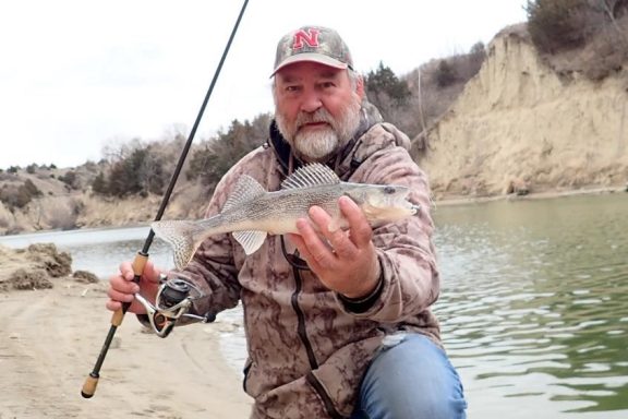 Shoreside angler holding a sauger. Photo by Daryl Bauer, Nebraska Game & Parks Commission.