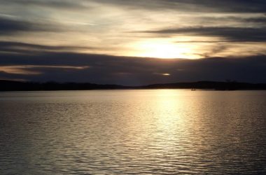 Sunset over water, boat on lake. Photo by Daryl Bauer.