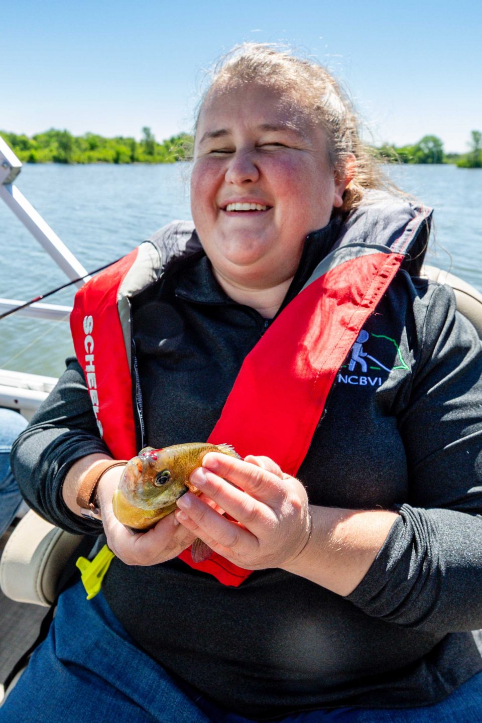 Charli Saltzman, a counselor with the Nebraska Commission for the Blind and Visually Impaired, holds and feels a bluegill she caught.