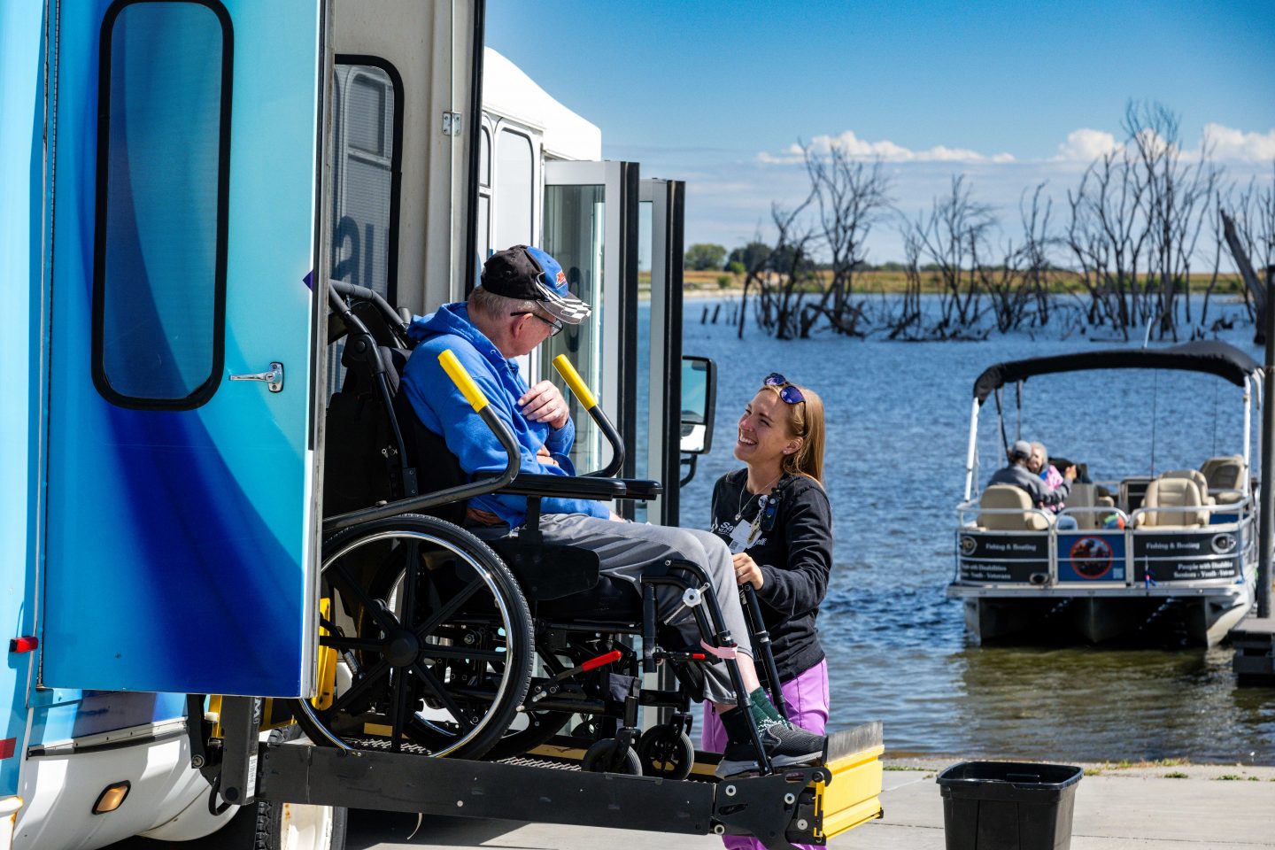 Kayla Massa, enrichment coordinator at Saunders Medical Center, helps resident Dennis Jeppson off the bus for an outing at Lake Wanahoo.