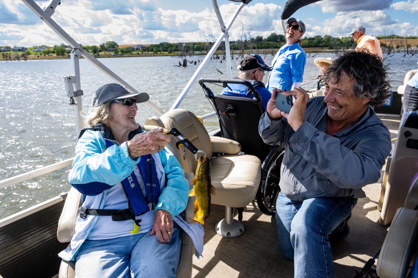 David Rudder, founder and head of Live Well. Go Fish., takes a photo of Joyce McIntosh, a resident of Saunders Medical Center Long Term Care in Wahoo, and the bullhead she caught during an outing at Lake Wanahoo.