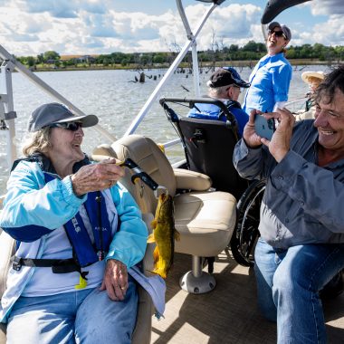 David Rudder, founder and head of Live Well. Go Fish., takes a photo of Joyce McIntosh, a resident of Saunders Medical Center Long Term Care in Wahoo, and the bullhead she caught during an outing at Lake Wanahoo.