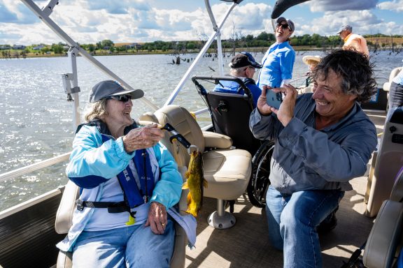 David Rudder, founder and head of Live Well. Go Fish., takes a photo of Joyce McIntosh, a resident of Saunders Medical Center Long Term Care in Wahoo, and the bullhead she caught during an outing at Lake Wanahoo.