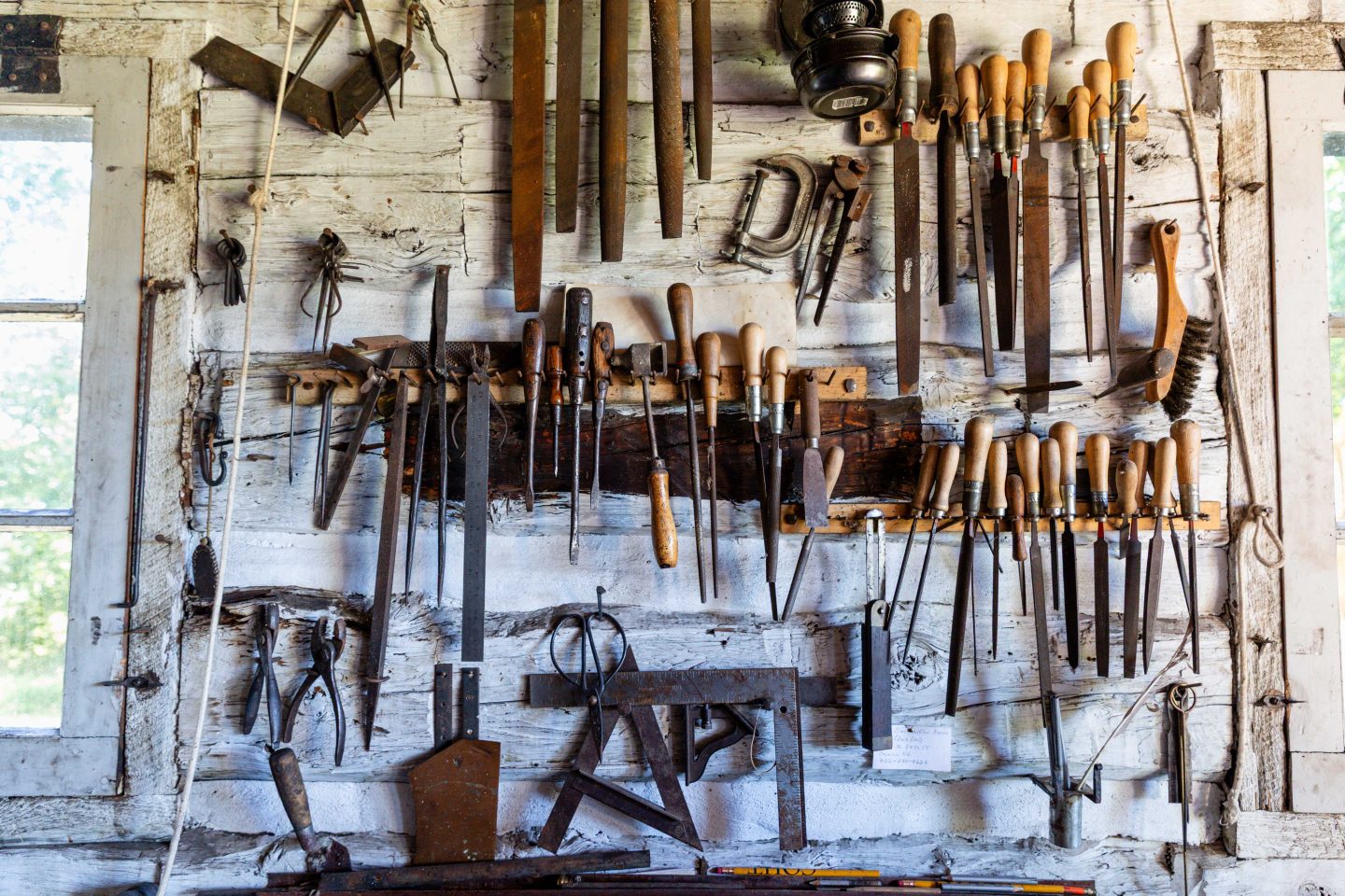 A variety of blacksmithing tools hanging on the wall at the blacksmith shop.