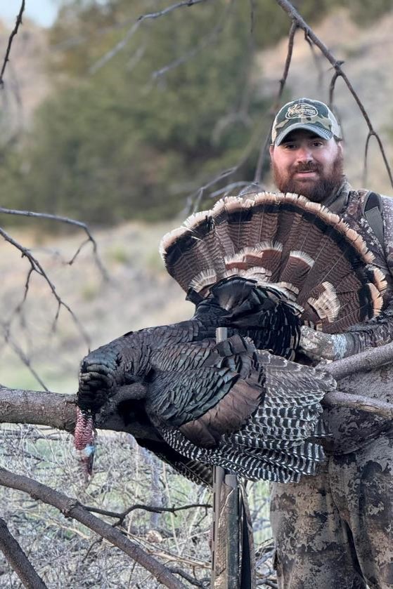 Successful turkey hunter posing with his bird.