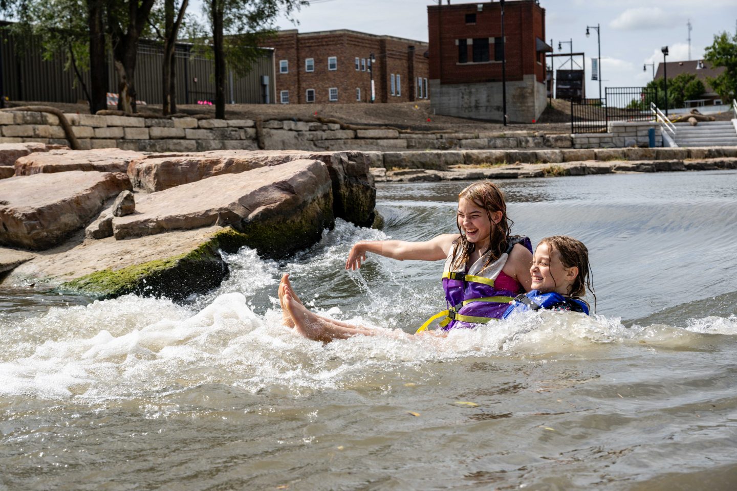 Elizabeth and Mya Silva of Norfolk body surf down one of the waves in Johnson Park.
