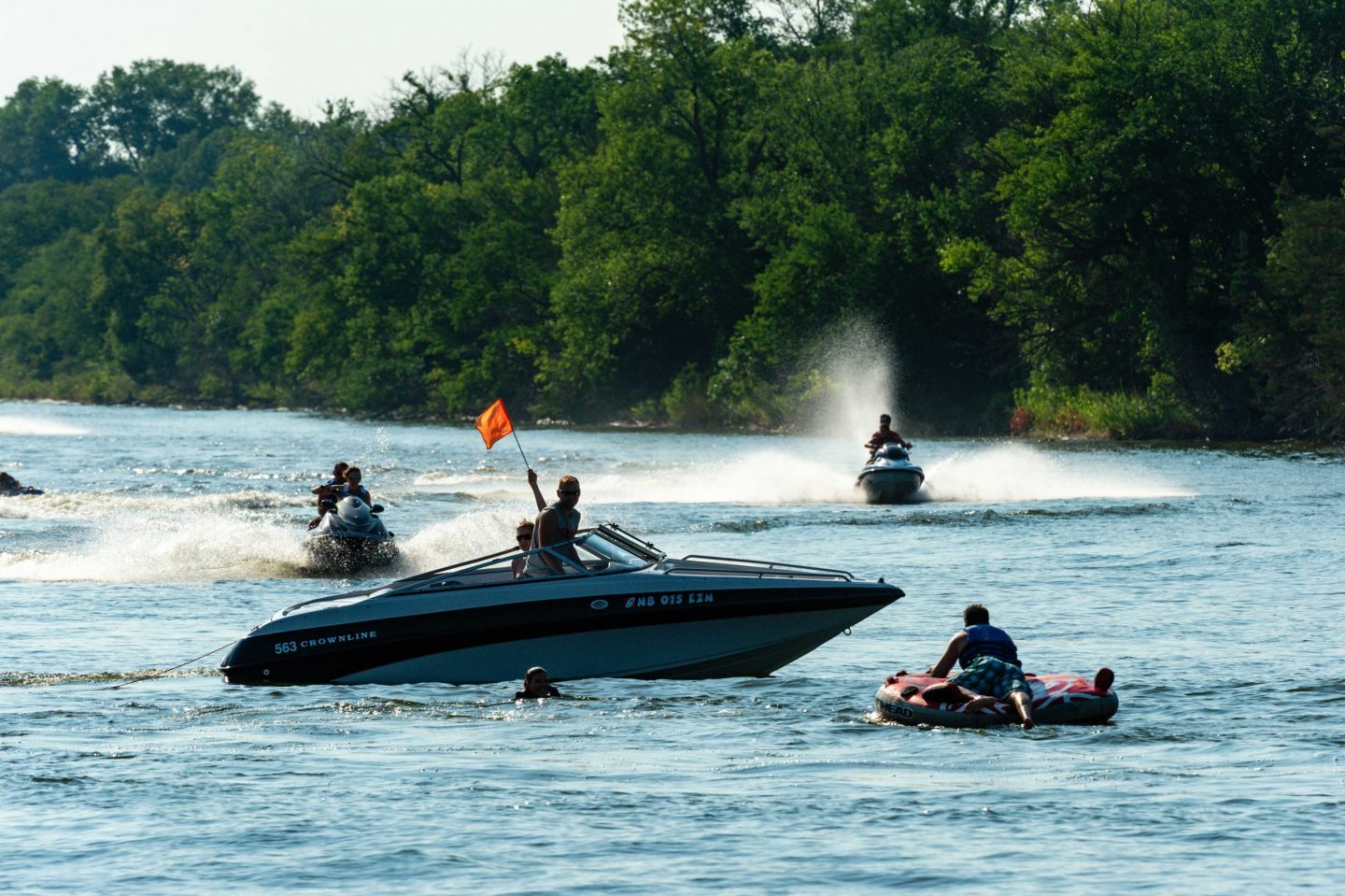 Boaters hold up the orange safety flag while the tubers they are pulling get back on board on Victory Lake at Fremont Lakes SRA in Dodge County.
