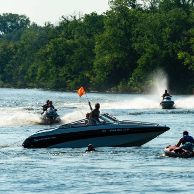 Boaters hold up the orange safety flag while the tubers they are pulling get back on board on Victory Lake at Fremont Lakes SRA in Dodge County.