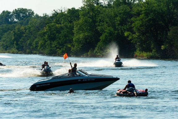 Boaters hold up the orange safety flag while the tubers they are pulling get back on board on Victory Lake at Fremont Lakes SRA in Dodge County.