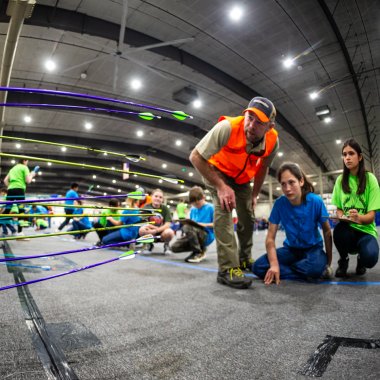 Safety official Nick Fischer, assistant superintendent at Indian Cave State Park, helps archers score their targets during the 2024 Nebraska National Archery in the Schools Program State Tournament at the Sandhills Global Event Center in Lincoln.