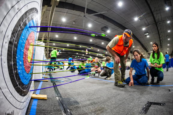 Safety official Nick Fischer, assistant superintendent at Indian Cave State Park, helps archers score their targets during the 2024 Nebraska National Archery in the Schools Program State Tournament at the Sandhills Global Event Center in Lincoln.